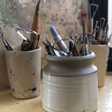 encaustic tools in pottery against a stone background