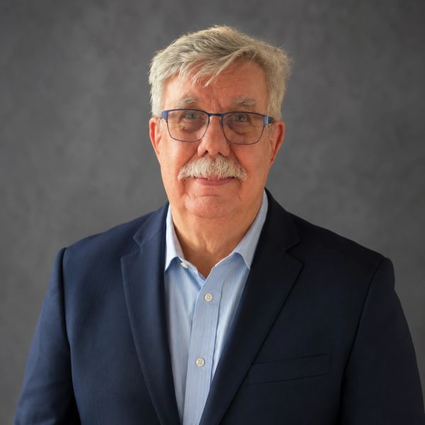 Older man with gray hair, mustache, glasses, dressed formally.