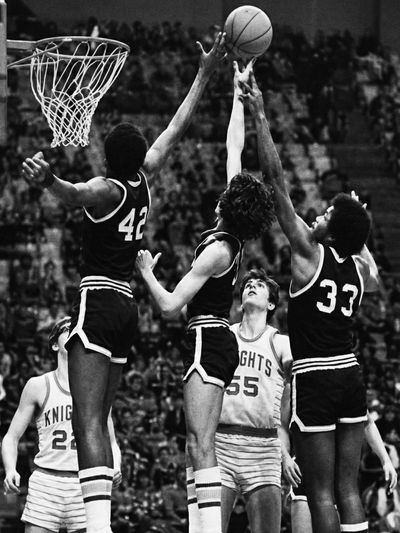 Vintage basketball game with players rebounding a shot.