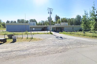 Single-story building with trees and gravel road.