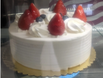 A white frosted cake topped with strawberries and blueberries.