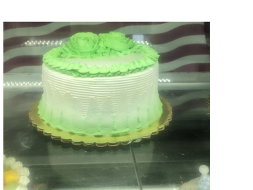 A white and green frosted cake with floral decorations.
