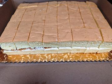 A large rectangular cake with cream filling, neatly sliced into squares.