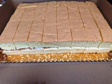 A large rectangular cake with cream filling, neatly sliced into squares.