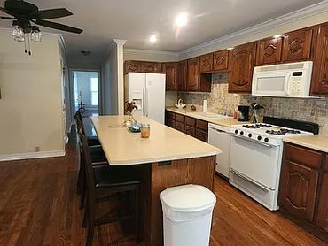 Open kitchen with white appliances and island.
