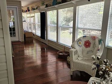 Bright porch with white wicker furniture seating.