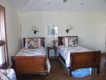 Simple bedroom with two wooden twin beds.