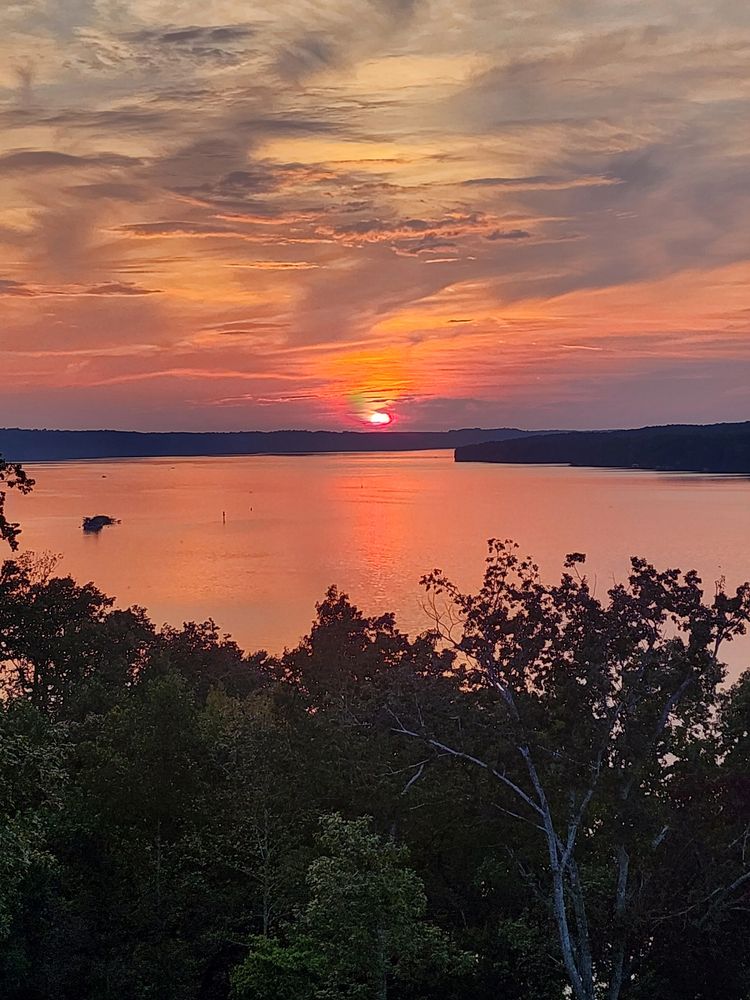 Sunset over water behind real estate logo.