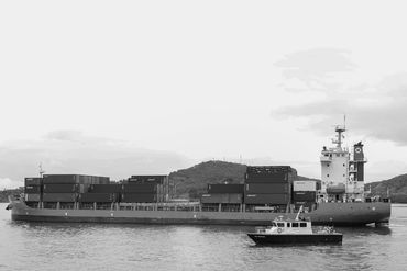 Cargo ship loaded with containers sailing near a pilot boat.