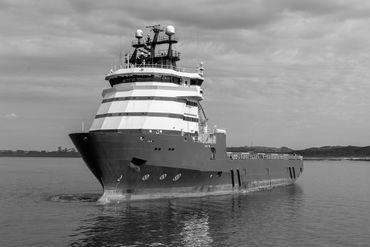 A large ship with a distinctive striped superstructure on calm water.