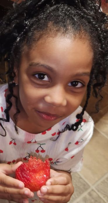 Little girl eating a Strawberry.