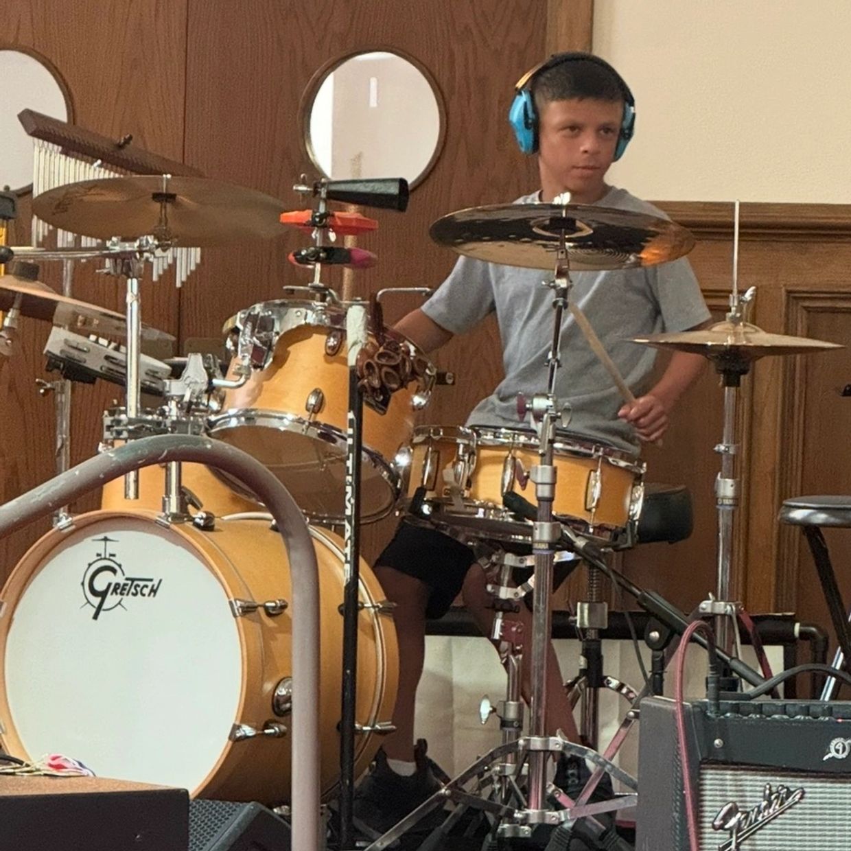 Boy playing drum set with headphones on.
