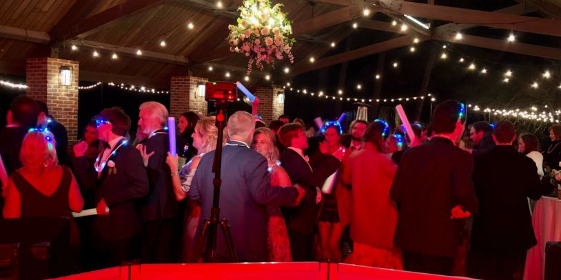 Modern wedding reception with packed dance floor and guests using glow sticks