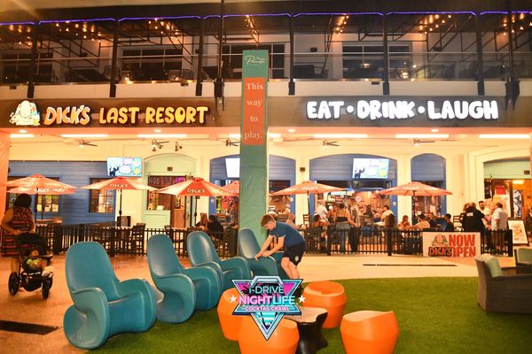 Night scene at Dick's Last Resort with outdoor seating and lively crowd.