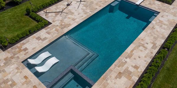 a exquisite pool design with travertine decking and pebble finish