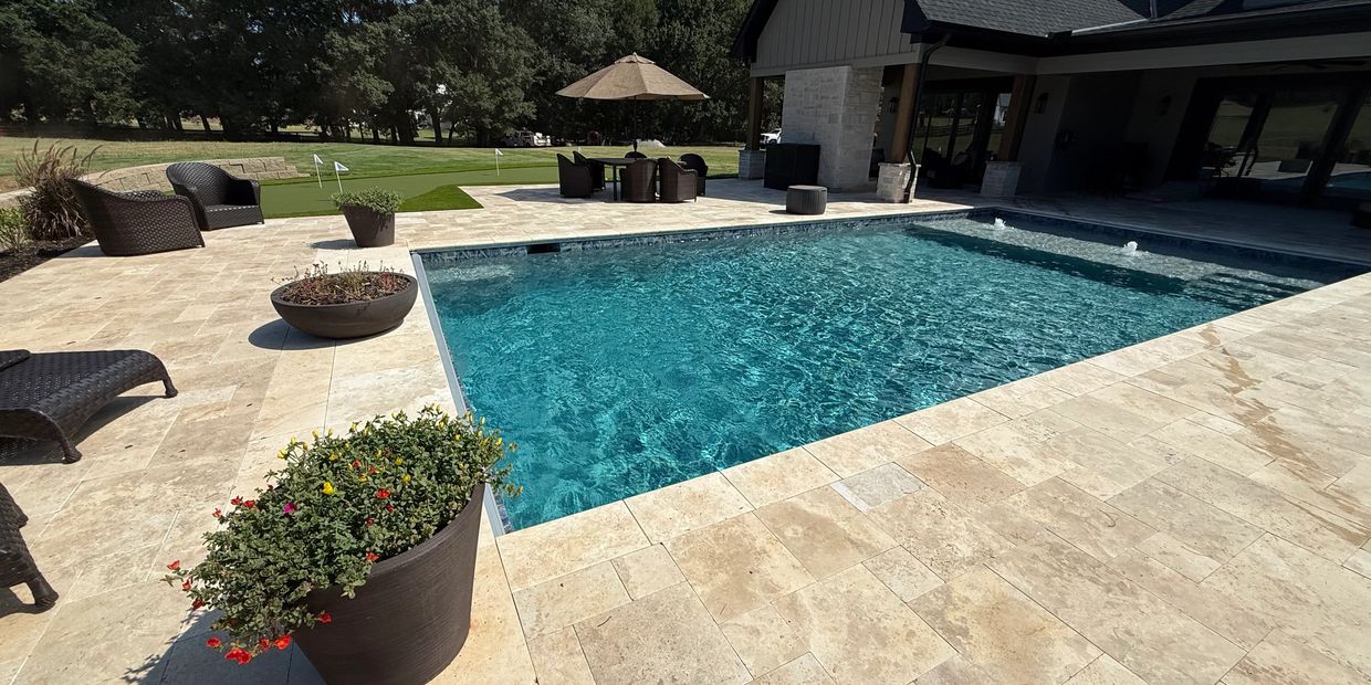 Modern backyard with a swimming pool and patio furniture under a sunny sky.