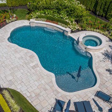 Elegant backyard pool with a spa and surrounding lounge chairs.