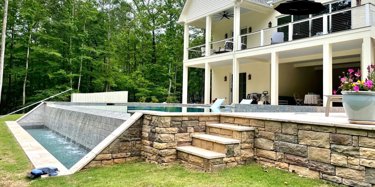 Modern house with a raised pool and stone retaining wall.