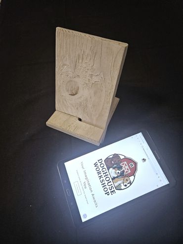 Wooden phone stand beside a tablet displaying Doghouse Workshop website.