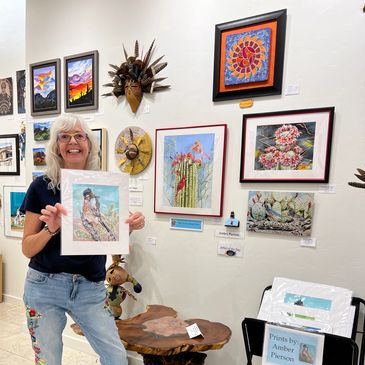 Woman holding artwork in gallery setting.