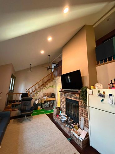 Living room with high vaulted ceiling and staircase.