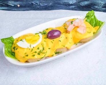 Peruvian dish topped with creamy sauce, egg, shrimp, and olive.