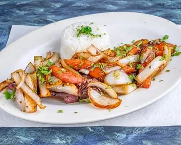 Grilled seafood and vegetables with rice on a white plate.