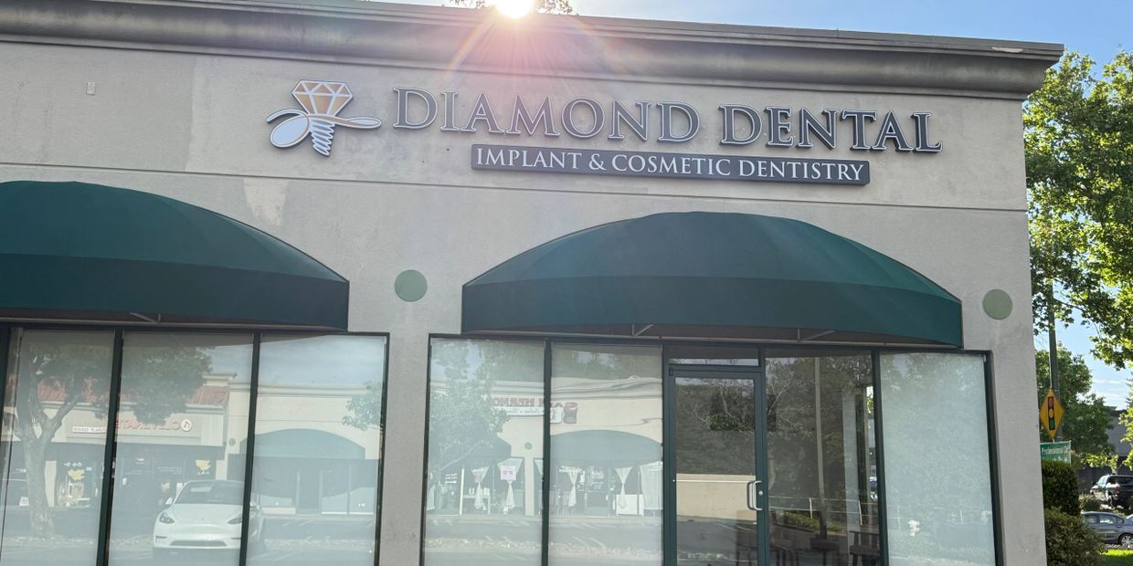 Diamond Dental storefront with green awnings and a bright sun flare.