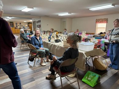 A group of elderly people socializing in a community room with tables and chairs.