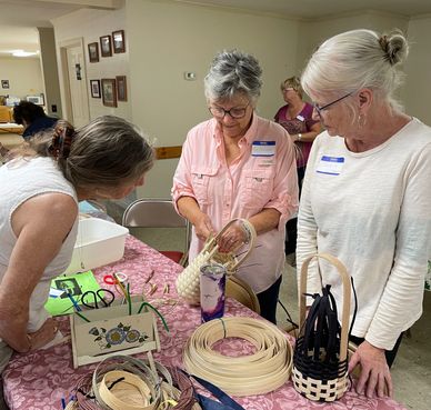 Joan demonstrates how to put on the rim for new weavers