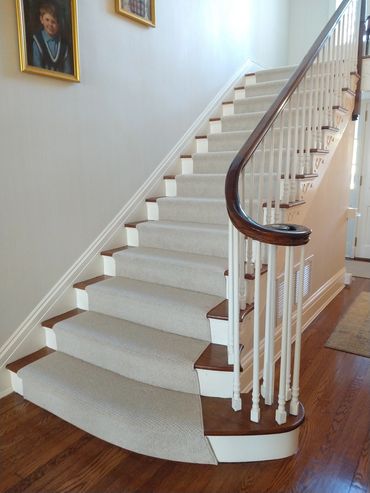 Slightly curved staircase with a light colored runner