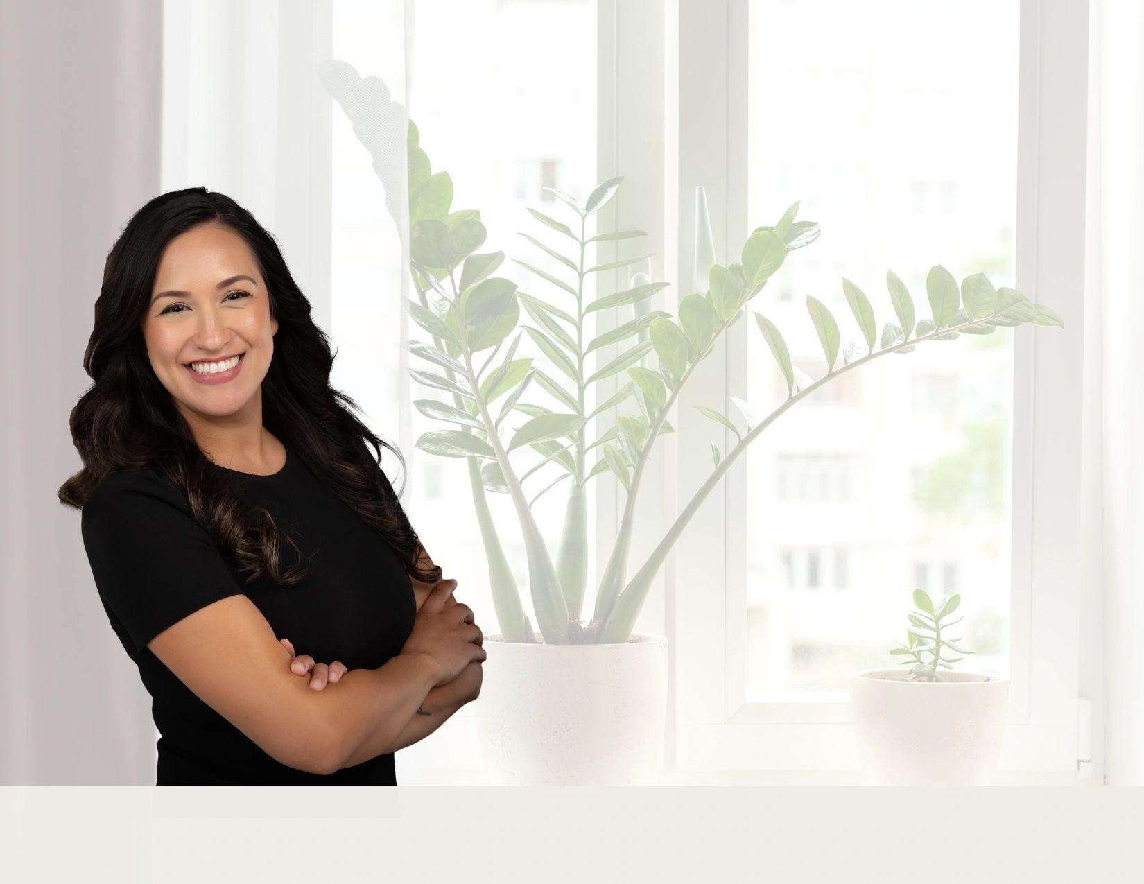 Confident woman smiling with arms crossed indoors.