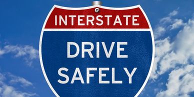 Interstate road sign with “Drive Safely,” Travel-Mingo International Drivers Permit.