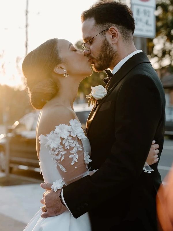 Bride and groom sharing a tender kiss at sunset on their wedding day.