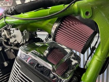 Close-up of a green motorcycle frame with air filter and engine details.