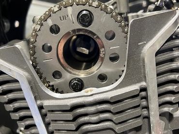 Close-up of a motorcycle engine's camshaft sprocket and timing chain.