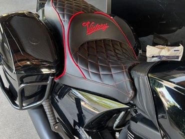 Close-up of a black Victory motorcycle seat with red stitching.