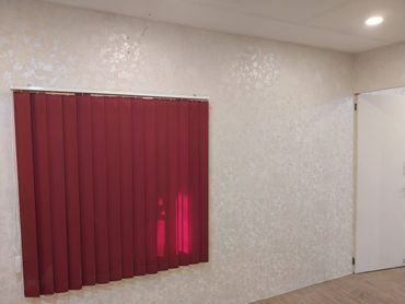 Room with closed dark red vertical blinds and a white door.