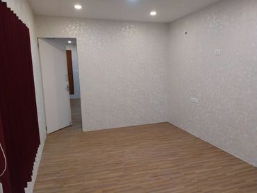 Empty room with wooden floor, light textured walls, and maroon vertical blinds.
