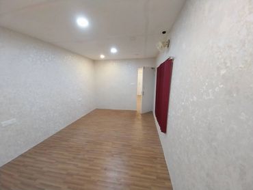 Empty room with wooden floor, white walls, and ceiling lights.