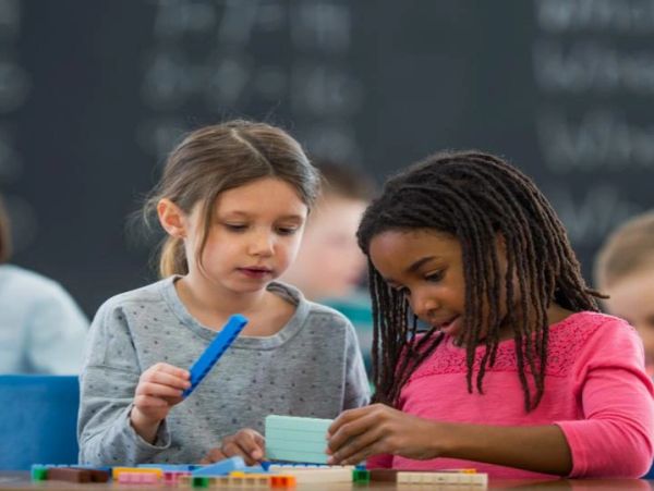 Two young girls collaborating on a classroom task with focus and curiosity.
