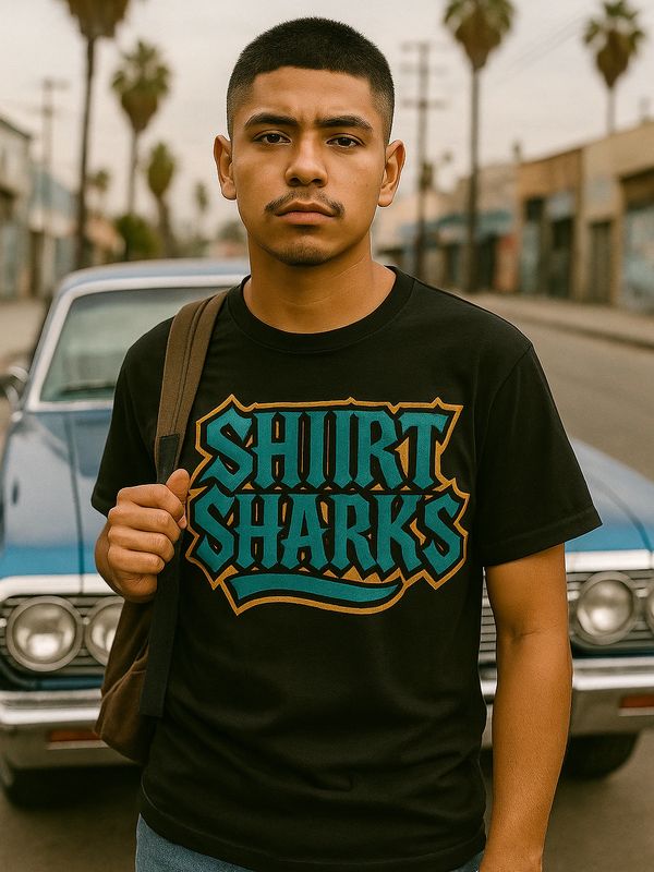Young man wearing a black 'Shirt Sharks' T-shirt standing in front of a blue vintage car.