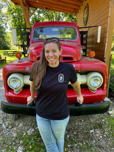 Smiling woman standing in front of a red vintage truck.