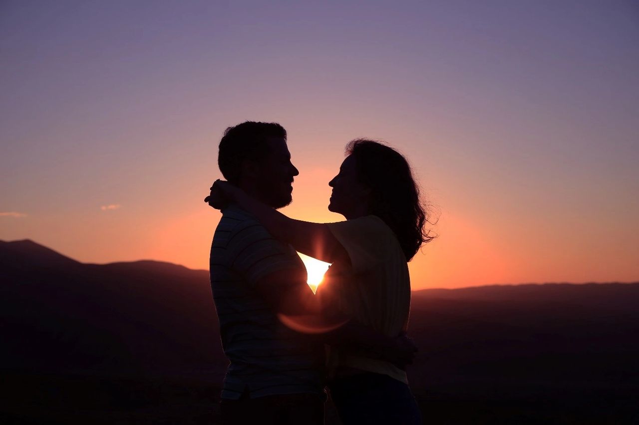 A woman with her arms wrapped around her partner’s neck. A woman with her arms wrapped around her partner’s neck.