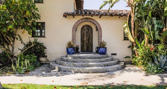 Rustic arched wooden door with stone steps and blue pots.