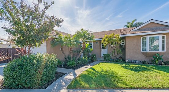 Suburban house with a well-maintained lawn and palm trees.