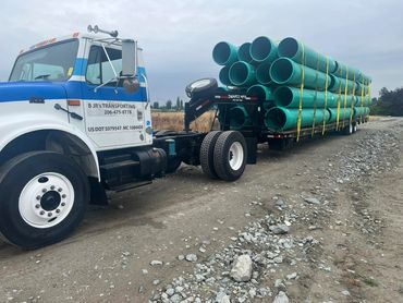Blue and white International day cab hauling green PVC pipe on a flatbed, Panama City, FL