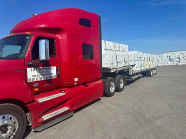 B JR's Transporting red semi with a flatbed of wrapped lumber, lumber hauling in Panama City, FL