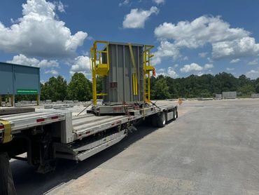 Tall industrial machinery with yellow safety rails secured on a flatbed trailer, Panama City, FL