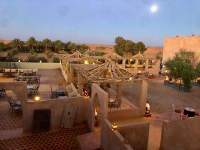 Outdoor seating area with pergolas and lanterns under a twilight sky.